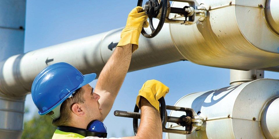 man turning valve stem in pipeline